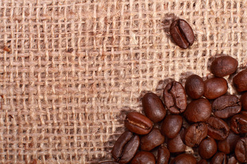 Naklejka premium Roasted coffee beans on burlap background