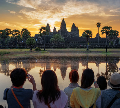 Asian tourists taking picture of Angkor Wat at sunrise