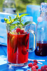 Fresh raspberry juice with mint in the garden on a blue backgrou