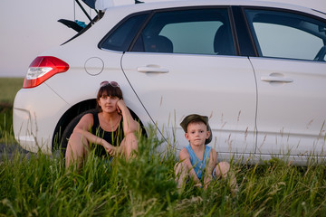 Mom and Son Sits Beside the Car While Waiting
