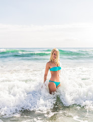 beautiful young blonde woman jumping big waves in sea