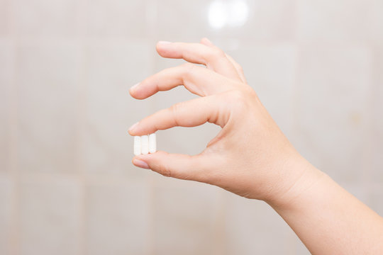 Female hand holding a pill