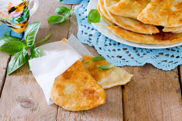 Tasty chebureks with fresh herbs on plate,on wooden background