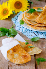 Tasty chebureks with fresh herbs on plate,on wooden background