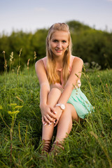 Fototapeta na wymiar Beautiful girl sitting on a grass, warm sunny day