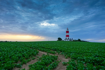 Fototapeta na wymiar Happisburgh Lighthouse in Norfolk at sunset during as passing storm.