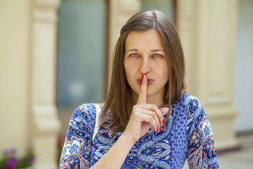 Woman has put forefinger to lips as sign of silence