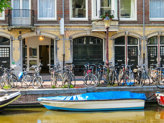 Fototapeta na wymiar The bicycles, boat and Facades of houses on the channel, Amsterdam, Netherlands