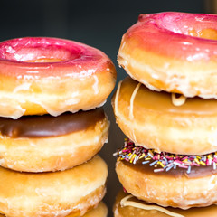 Stacks of Glazed Doughnuts with colourful sprinkles, chocolate,