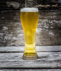 Beer in glass background old wood.