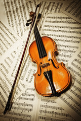 Obraz na płótnie Canvas Old wood violin lying on musical notes