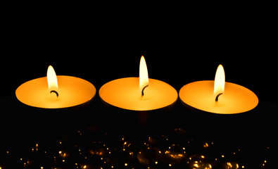 Three candles against a dark background