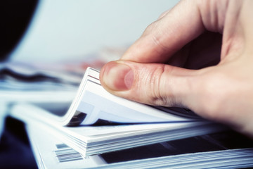 Man's hand turned over a stack of magazines