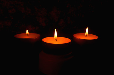 Three candles against a dark background