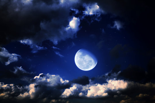 moon and stars in a cloudy night blue sky