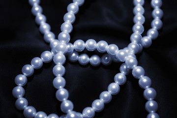 white pearl necklace on a black silk