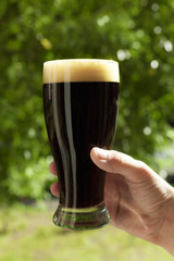 hand holding glass of dark beer