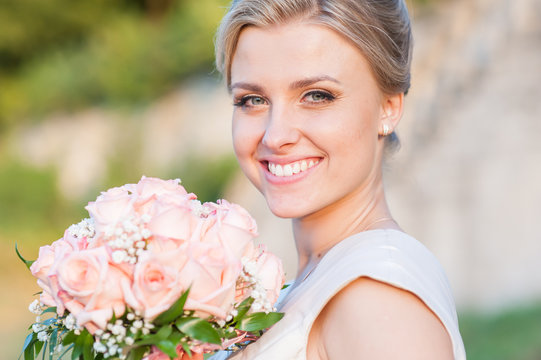 Beautiful young bride with wedding bouquet before wedding ceremony