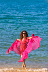 Travel and Vacation. Freedom Concept. Beautiful Girl With pink Scarf on The Beach enjoying summer.