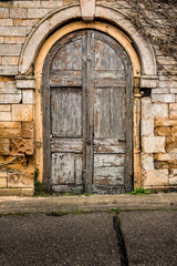 Fototapeta na wymiar Old decaying wooden double doors in a stone archway