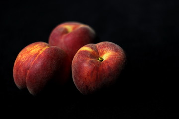 Fototapeta na wymiar Three tasty juicy peaches on a black background 