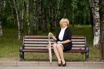 Elderly business woman in jacket sittin on bench