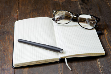 Fototapeta premium Reading glasses and notepad on wooden background