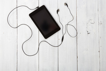 Tablet pc with headphones on wooden background