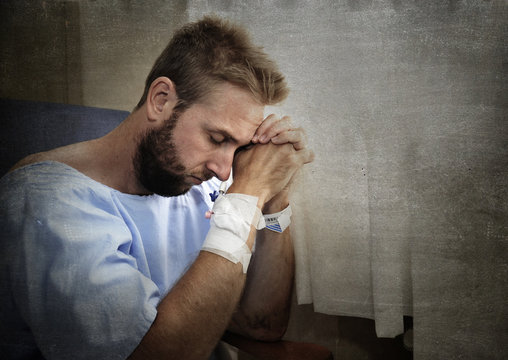 young injured man in hospital room sitting alone in pain worried