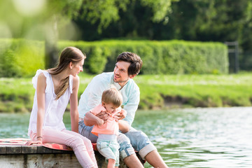 Fototapeta premium Glückliche Familie am See sitzt auf Steg