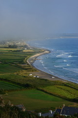 St.Ouen's Bay, Jersey, U.K.   Summer fog encroaches over a surfing beach at high tide.