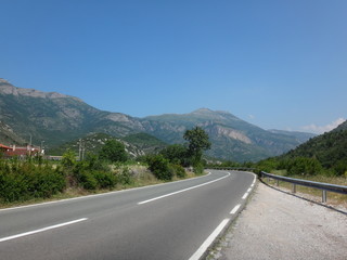 Naklejka premium Дорога трасса в горахгорах летним днем в окружении зелени