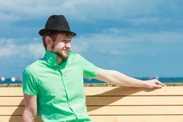 young hipster man sitting on bench near the sea outdoor