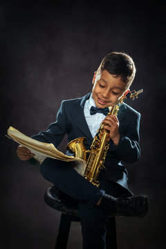 six years old boy sit with saxophone