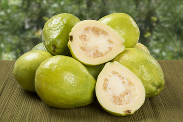 A white guava cut in a alf in over some entire white guavas over