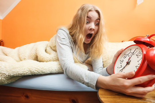 Woman waking up late turning off alarm clock. Photos | Adobe Stock