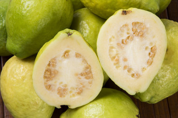 A white guava cut in a alf in over some entire white guavas over