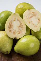 A white guava cut in a alf in over some entire white guavas over