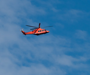 Orange helicopter in flight on Blue Sky