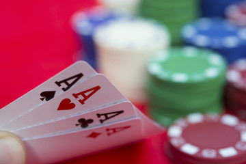 poker player holding 4 Ace of pokers beside lots of chips