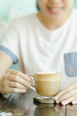 Hot cappuccino coffee on the table with woman background