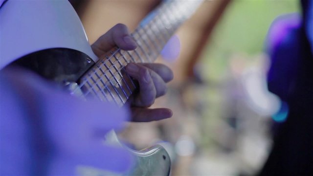 Playing guitar. Guitarists hands playing chords on electric guitar. Musician performing solo during concert in a night club. Close-up