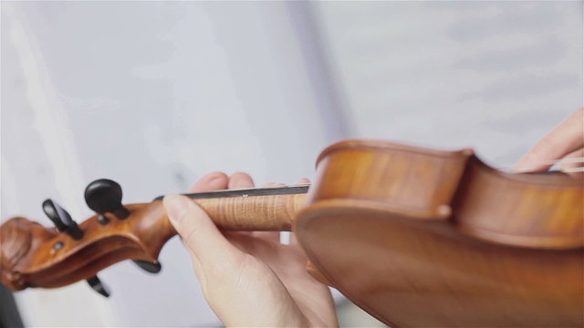 Playing violin with fingers. Female hand plucking strings of violin. Close up