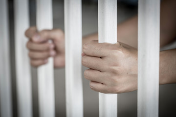 Hands of the Asian prisoner behind the jail
