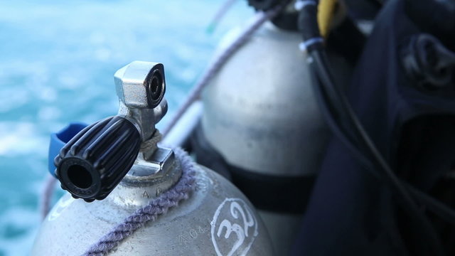 assistant unbinds silver metal oxigen cylinder diving from boat	