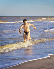 Athletic Man Running in water on Beach