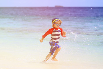 little boy splashing water on tropical beach