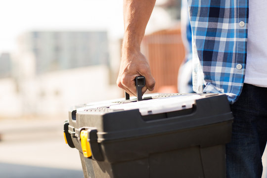 close up of builder carrying toolbox outdoors