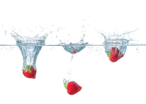 Fototapeta Erdbeeren fallen ins Wasser mit Spritzern
