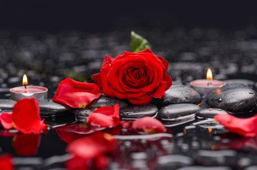 Red rose with petals with candle and therapy stones 